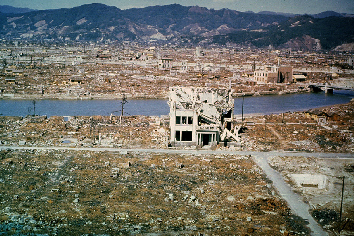 A colored photo showing Hiroshima after the explosion. A few concrete structures are still standing, though they are mostly rubble. The rest of the shot shows the city flattened by the blast. The shot extends all the way to the mountains in the distance. A colored photo showing Hiroshima after the explosion. A few concrete structures are still standing, though they are mostly rubble. The rest of the shot shows the city flattened by the blast. The shot extends all the way to the mountains in the distance.