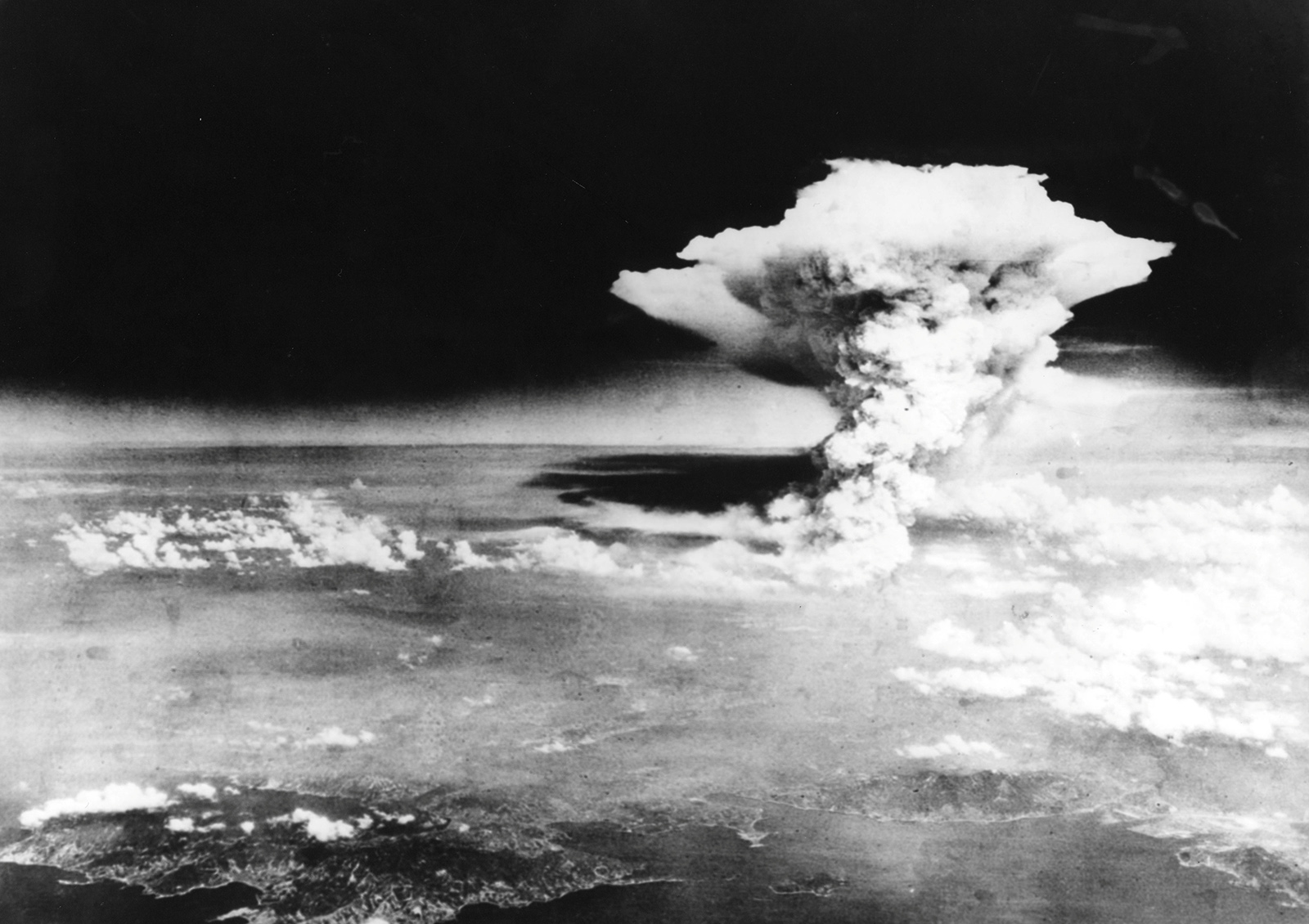 A photo taken from the Necessary Evil showing the mushroom cloud towering above the city of Hiroshima. The cloud occupies the center left of the shot and there is denser cloud covering the lower portion of the photos. However, in the bottom part of the photo, you can see the coast line which provides scale for how enormous the cloud is. A photo taken from the Necessary Evil showing the mushroom cloud towering above the city of Hiroshima. The cloud occupies the center left of the shot and there is denser cloud covering the lower portion of the photos. However, in the bottom part of the photo, you can see the coast line which provides scale for how enormous the cloud is.