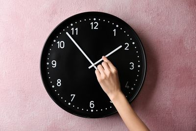 person changing the time on a big wall clock