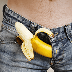 A banana poking out of a man's jean fly.